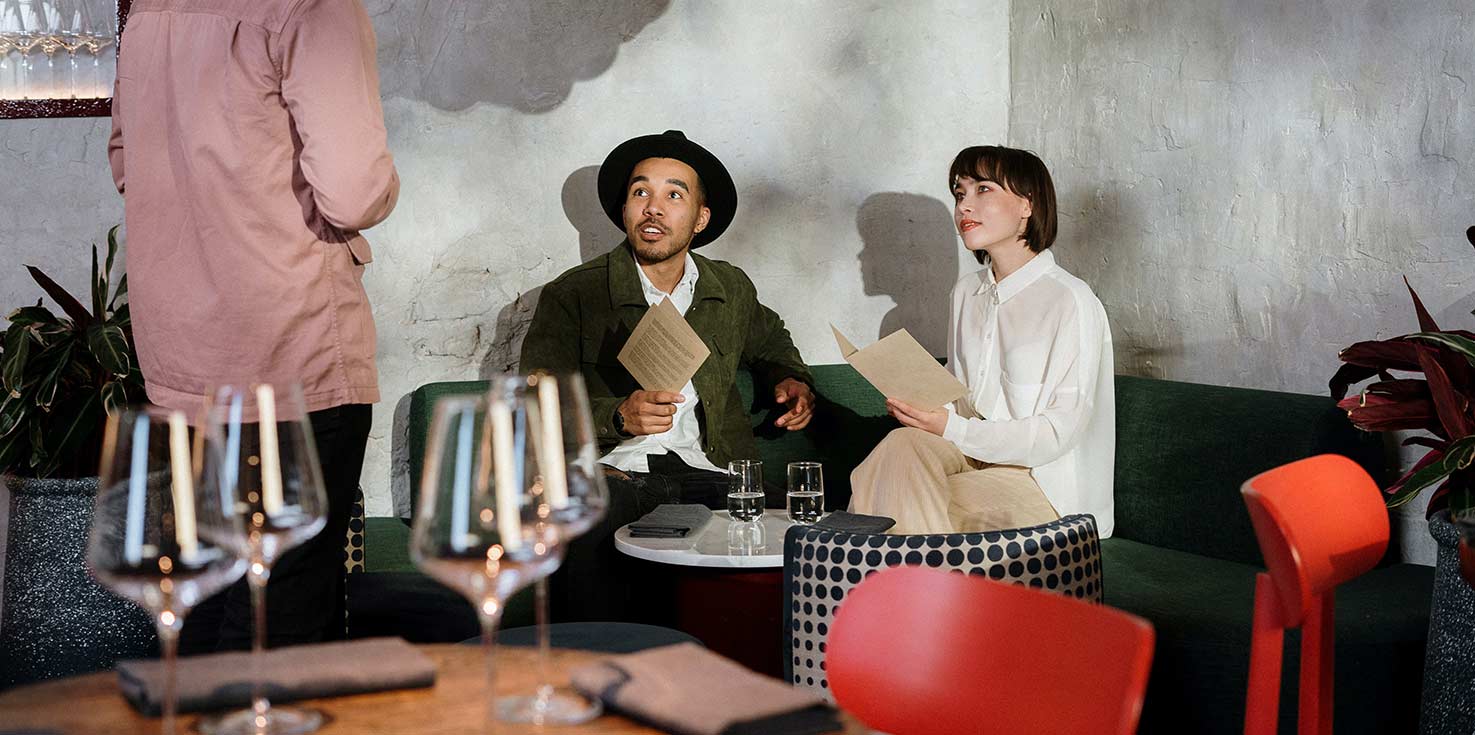 two people sitting at a table looking at the waiter